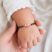 Load image into Gallery viewer, Child's hand wearing a bracelet with a butterfly charm held by an adult hand against a neutral background
