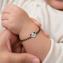 Load image into Gallery viewer, Baby's hand wearing a bracelet with a panda charm held by an adult.
